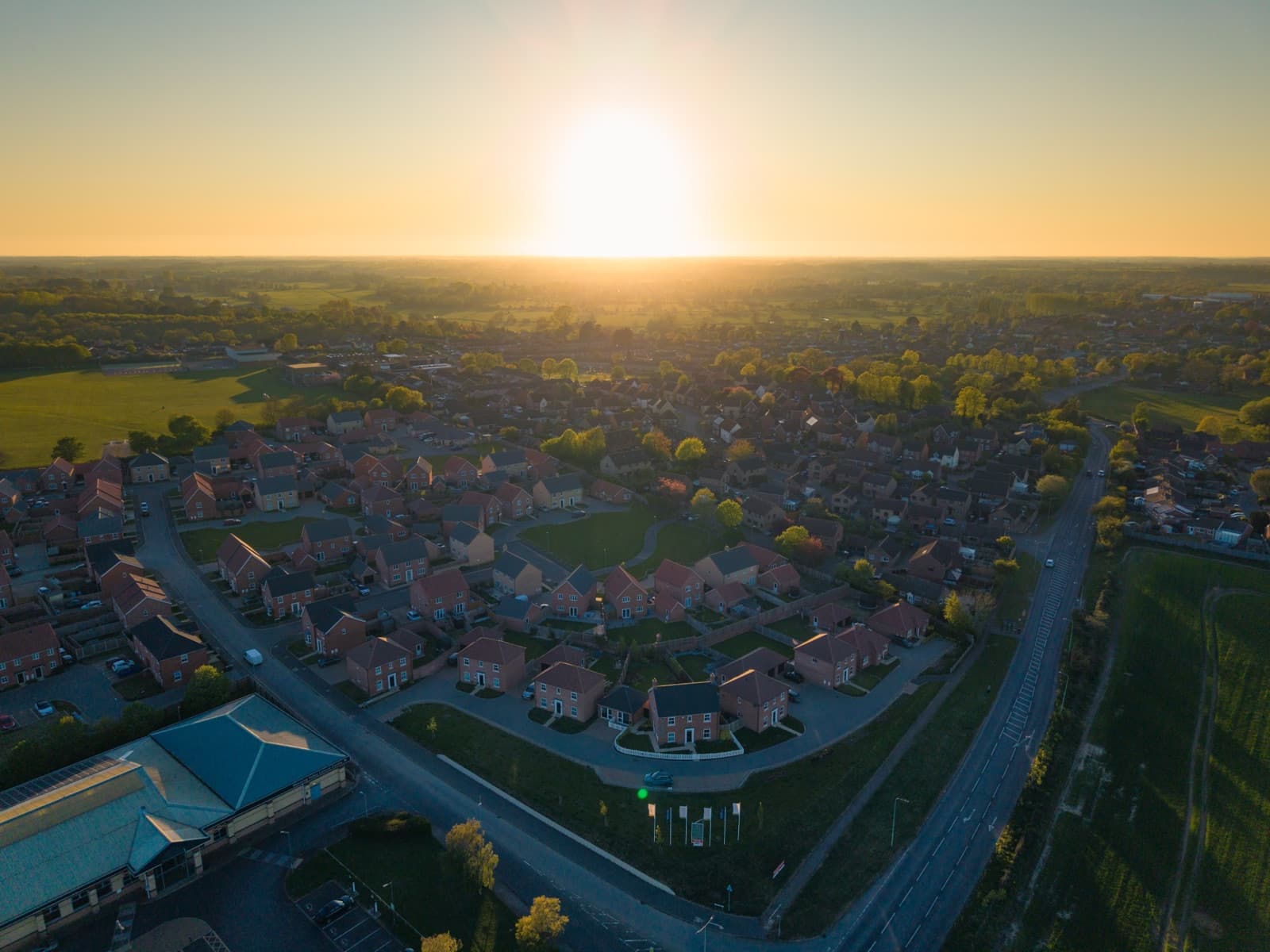Golden-hour aerial of a completed new-build estate — solicitors for buyers of new homes in Norfolk and Suffolk
