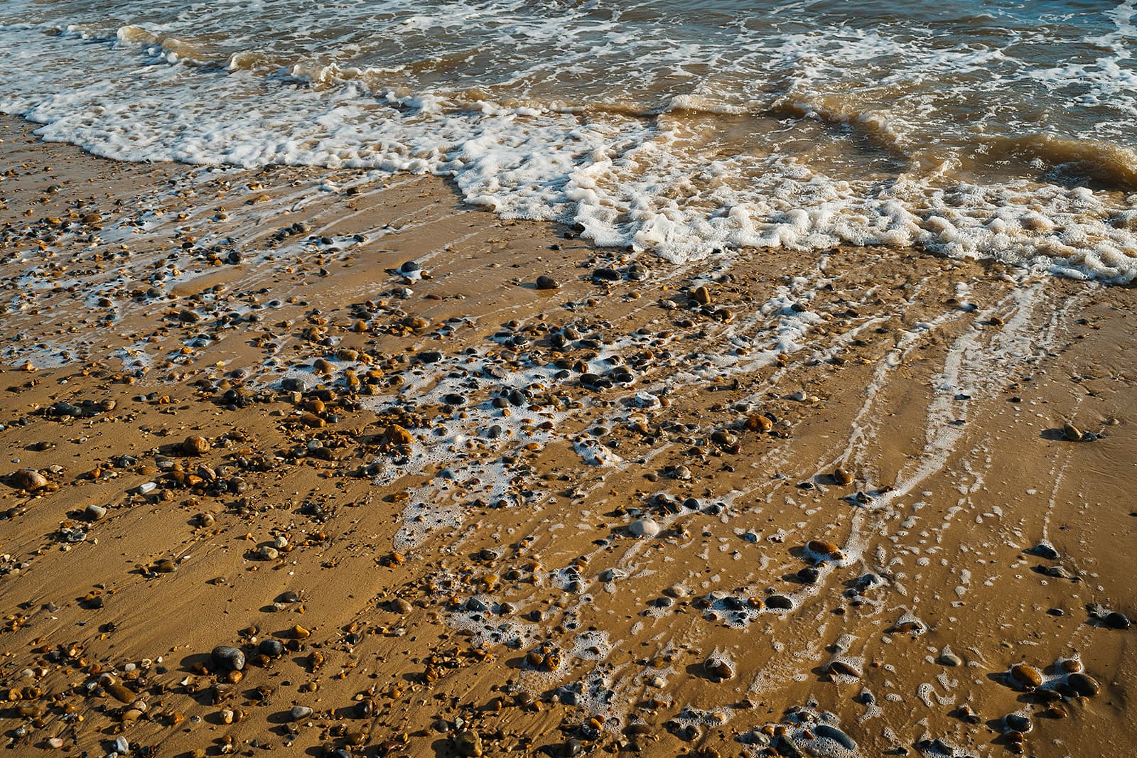 Waves washing over the pebbled shoreline on the Suffolk coast