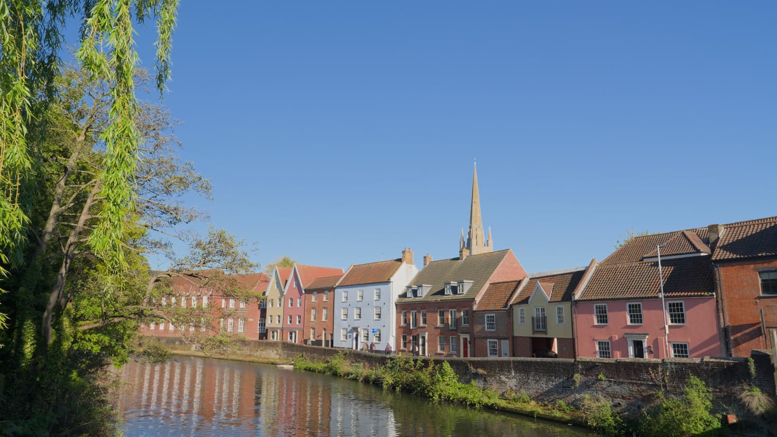 Colourful riverside houses on Quayside in Norwich, with the cathedral spire behind