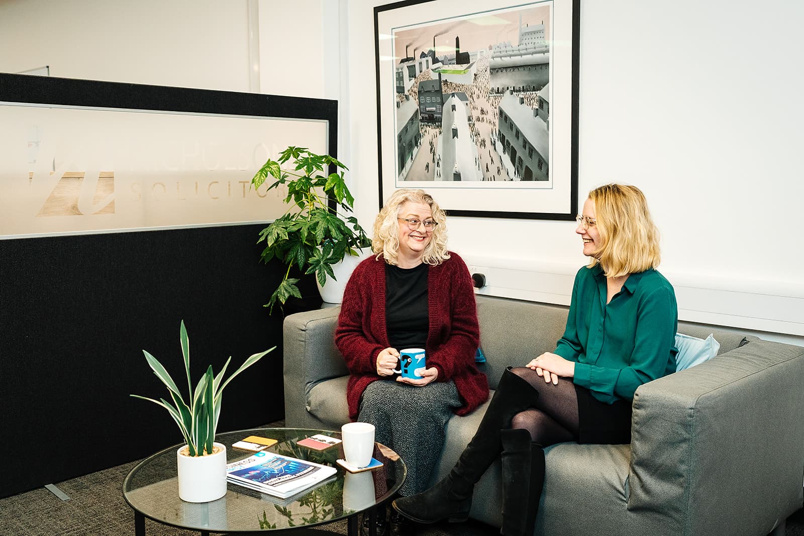 Two people chatting over coffee on a sofa at the Nicholsons Solicitors office — talking through the cost of a divorce